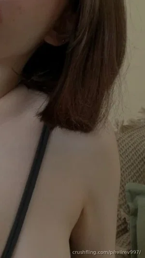 Woman with shoulder-length brown hair wearing a black strap top, indoors.
