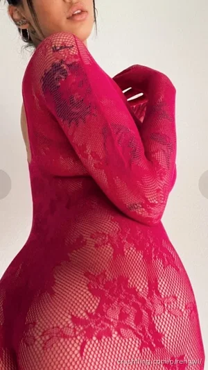 Woman in red lace bodysuit, side profile, indoor setting.
