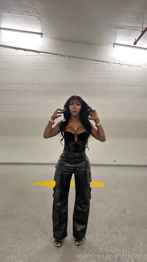 Woman in black lace top and leather pants posing in a garage.