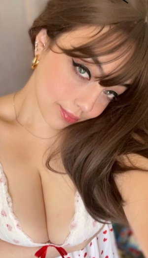 Woman with brown hair in white lace top taking indoor selfie.