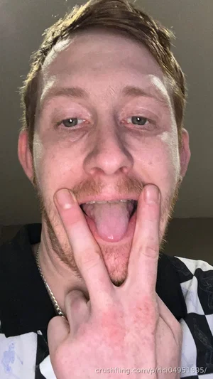 man with short brown hair and beard making a peace sign with tongue out, wearing black and white