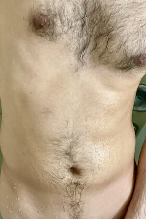 Hairy male torso with visible nipples and navel indoors.
