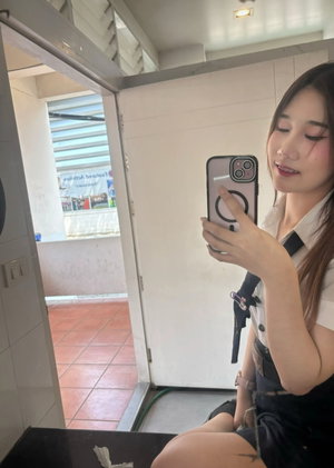 Woman in uniform taking mirror selfie in bathroom.