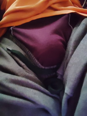 Close-up of fabric and clothing, including purple and gray garments, possibly on a bed.