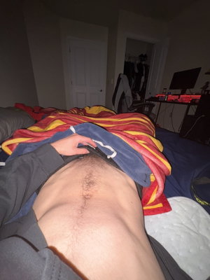 Man lying on bed with shirt lifted in bedroom.