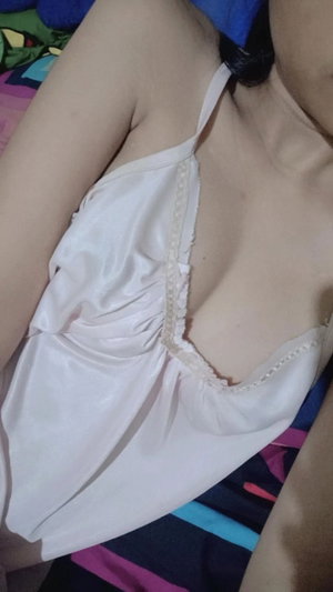 Slim woman in white slip on colorful bed.