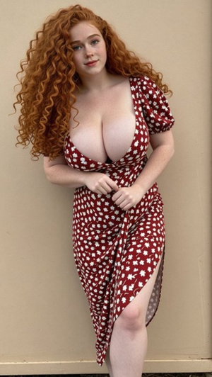 Curvy redhead woman in floral dress posing indoors.