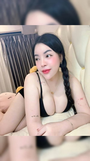 Asian woman with braided hair in black bra on bed.