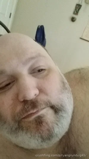 Bald man with gray beard, shirtless, indoors, close-up selfie.