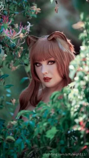 Woman with cat ears and brown hair peeking through green foliage outdoors.