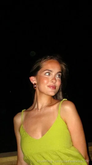 Woman in lime green spaghetti strap top, indoor setting, dark background.