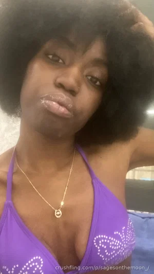Woman with afro wearing purple top with rhinestones, indoors.