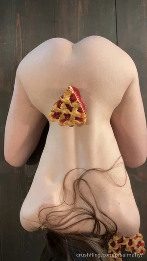 Woman with bare back, brown hair, wearing decorative pizza-shaped body jewelry, facing away from