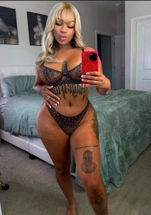 Curvy blonde woman in leopard lingerie taking bedroom selfie.