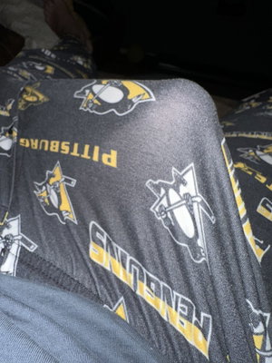 Person wearing Pittsburgh Penguins patterned pants indoors.