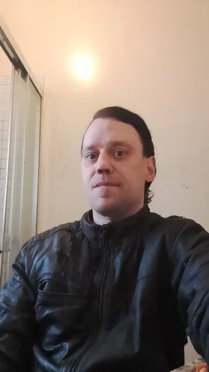 Man in black leather jacket indoors, facing camera.