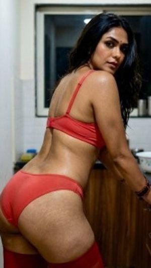 Woman in red lingerie posing in kitchen, back view, dark hair, curvy figure.