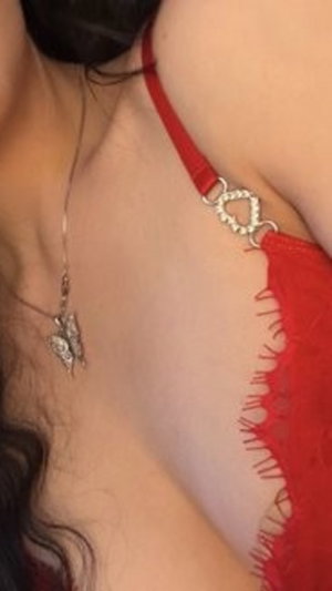 Woman in red lace lingerie with necklace, close-up on chest and neck.