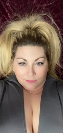 Blonde woman in dark top lying on purple surface.