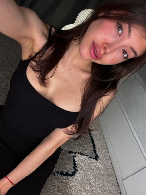 Woman with long dark hair in black top lying on carpet indoors.