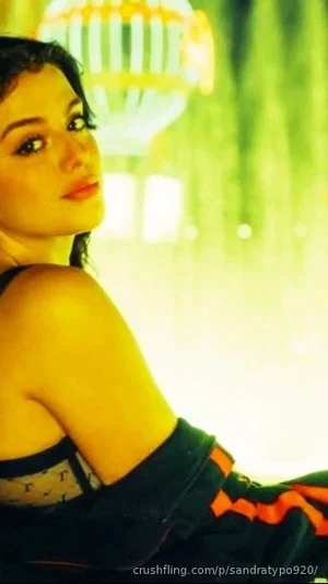 Woman in black and orange outfit, posing indoors with warm lighting.