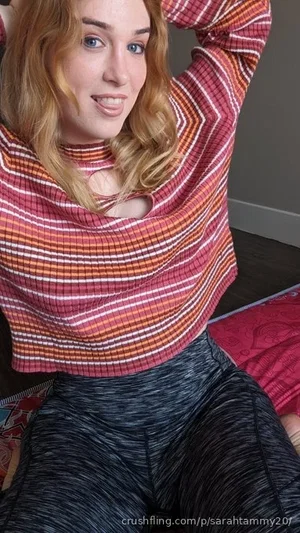 Woman with blonde hair in striped top and leggings, sitting indoors.