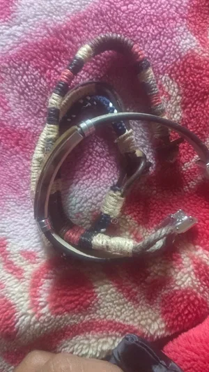 Hand holding a coiled braided cord with metal rings on a red and white patterned towel.