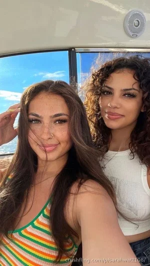 Two women in colorful tops on a boat, smiling at the camera.