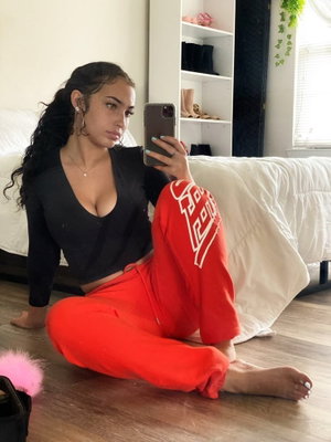 Woman in black top and red pants taking selfie in bedroom.