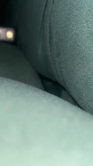 Close-up of dark fabric and soft material, possibly clothing or bedding, in dim lighting.