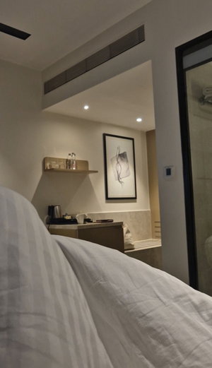 Hotel room interior with bed, desk, and bathroom visible in background.