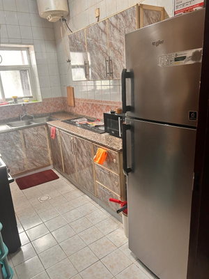 Kitchen with stainless steel fridge, marble cabinets, and tiled floor.