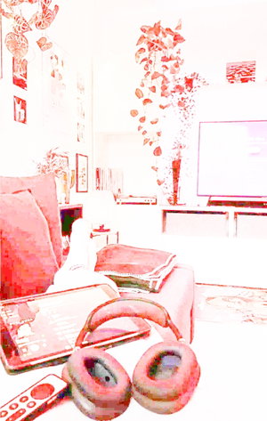 Living room with pink couch, headphones, tablet, and plants; indoor setting.