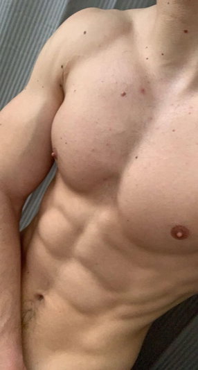 Shirtless man with defined abs and chest, standing indoors.