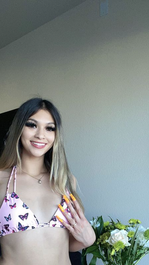 Smiling woman with long hair in pink butterfly bikini indoors.