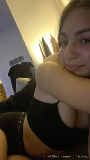 Woman in black crop top and underwear posing indoors, arms crossed near face.