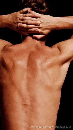 Shirtless man with muscular back, hands clasped behind head, dark background.