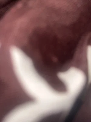 Blurred close-up of skin with white markings, possibly body paint or shadow.