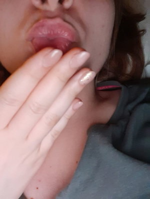 Woman with open mouth and hand near lips in dark top.