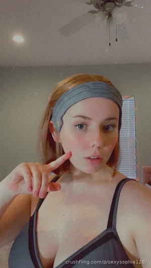 Woman with short hair wearing gray sports top and headband, posing indoors.