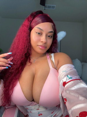 Curvy woman with red hair in pink bra taking indoor selfie.