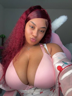 Woman with red hair in pink bra taking selfie in chair.