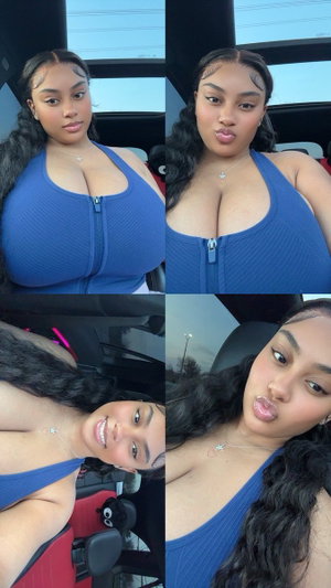 Woman with long dark hair in blue zip-front top, posing in car interior.
