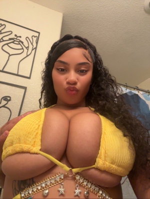 Woman with curly dark hair wearing yellow top indoors.