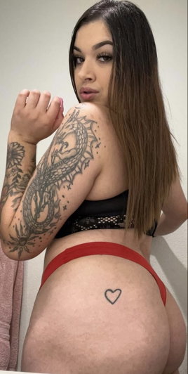 Brunette woman with tattoos wearing red underwear indoors.