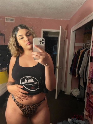 Curvy woman in tank top and leopard underwear taking mirror selfie indoors.