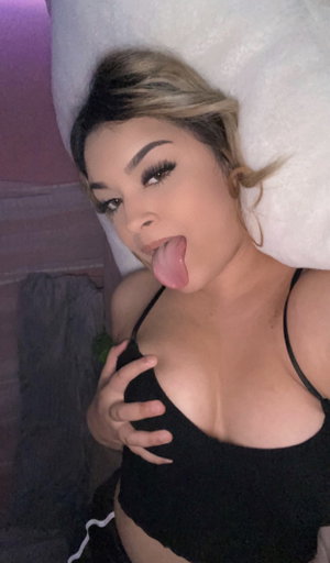 Blonde woman in black top lying on bed.