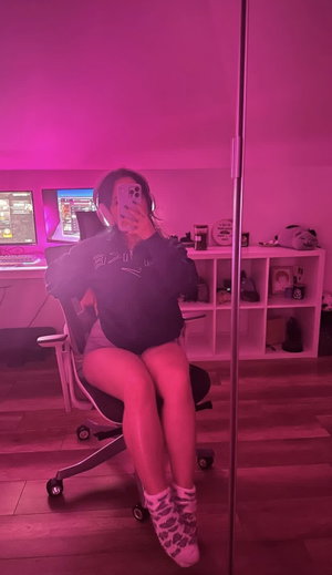 Woman in hoodie and shorts sits in gaming chair.