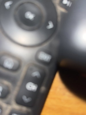 Blurry close-up of black remote control on wood.