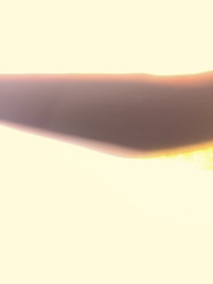 Blurred silhouette of a body curve against bright background.